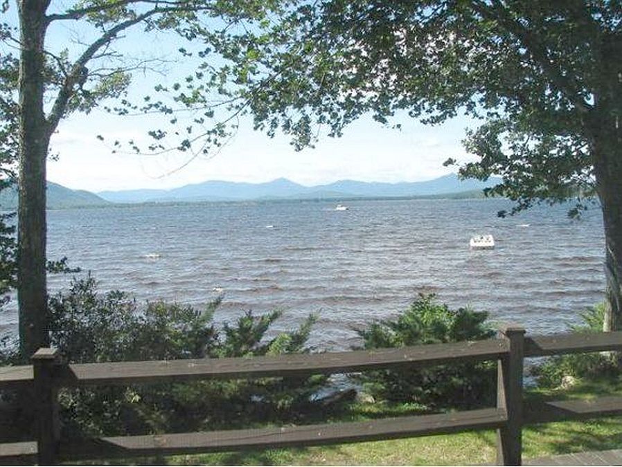 Large deck sits at the edge of Ossipee Lake with White Mountains seen on other side